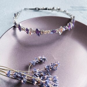 May include: A silver headband with a row of clear and purple rhinestones. The headband is on a purple plate with dried lavender flowers.