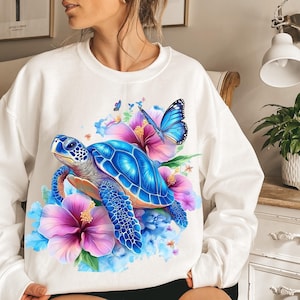 May include: White sweatshirt with a colourful design of a blue sea turtle, pink and blue flowers, and butterflies. The artwork has a watercolour effect. The sweatshirt is a relaxed, comfortable style, suitable for everyday wear. The design is eye-catching.