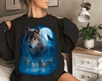 May include: Black sweatshirt featuring a detailed illustration of a wolf with piercing eyes, set against a backdrop of a full moon and a pack of wolves. The design incorporates shades of blue and gray.