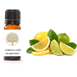 Op de afbeelding: Een klein bruin glazen flesje met een zwarte dop, met het label "Lemon & Lime Fragrance". Het flesje ligt naast een groep gesneden citroenen en limoenen, met groene bladeren.