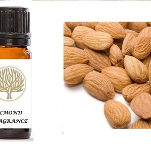 Op de afbeelding: Een klein bruin glazen flesje met een zwarte dop. Het flesje heeft een wit etiket met een gouden boomontwerp en de tekst "ALMOND FRAGRANCE".