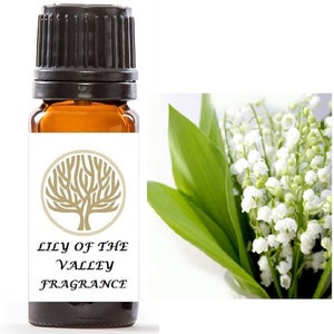 Op de afbeelding: Een klein amberkleurig glazen flesje met een zwarte dop, met het label "Lily of the Valley Fragrance". Het flesje is omgeven door een witte achtergrond en een klein boomlogo. De afbeelding toont ook een boeket witte lelietjes-van-dalen met groene bladeren.