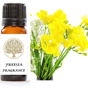 May include: A small brown glass bottle with a black cap and a white label. The label has a gold tree logo and the text "FREESIA FRAGRANCE". The bottle is next to a bouquet of yellow freesia flowers.
