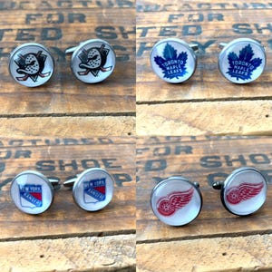 May include: Set of six silver cufflinks featuring NHL team logos. The logos are for the Anaheim Ducks, Toronto Maple Leafs, New York Rangers, and Detroit Red Wings.