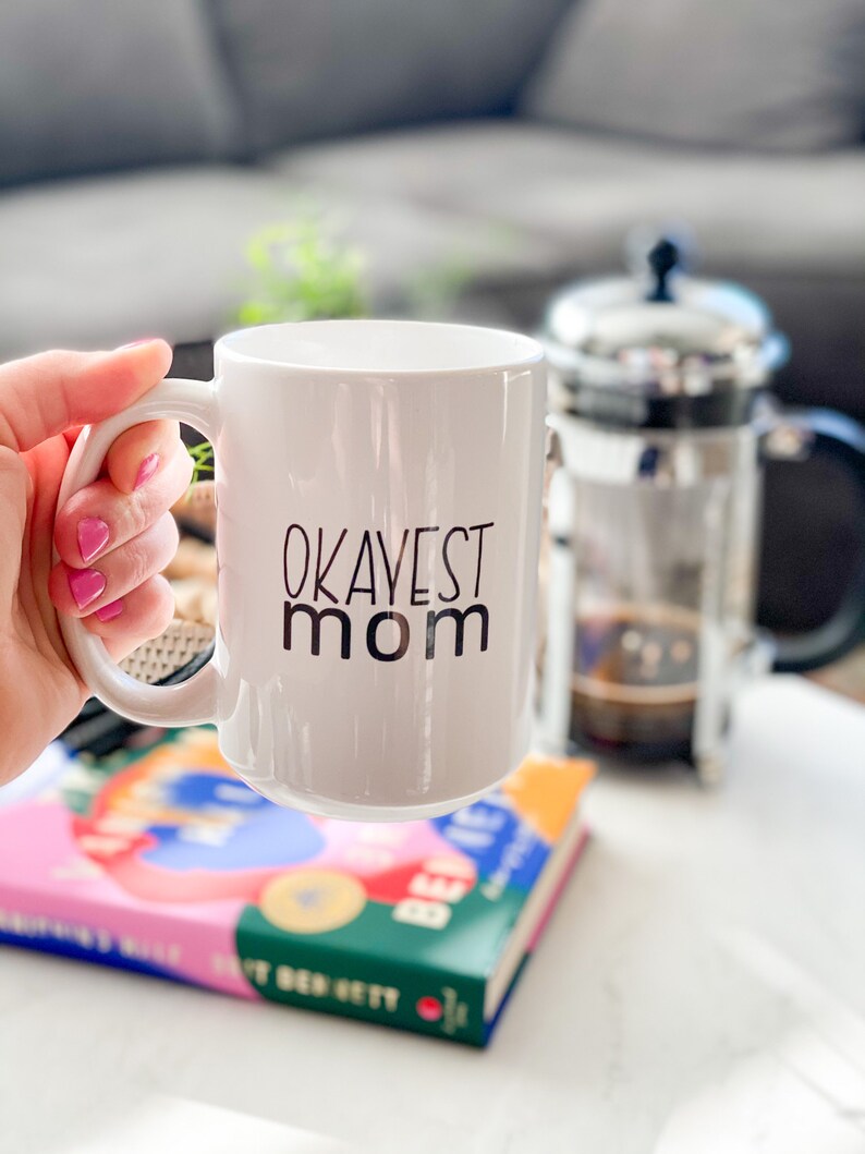 okayest mom ceramic mug with hand holding
