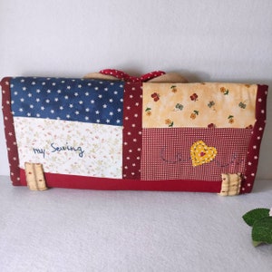 May include: A red, white, and blue patchwork fabric sewing case with the words "My Sewing" embroidered on the front. The case has a heart-shaped patch with a yellow button in the center.