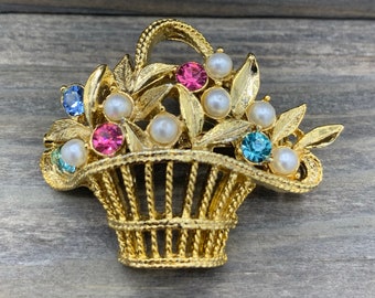 Broche tipo cesta, firmado por Gerry's, tono dorado, las flores son perlas de imitación y piedras preciosas de colores.