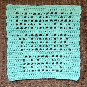 Puede incluir: Un paño de cocina cuadrado de ganchillo de color turquesa claro con un patrón repetitivo de agujeros.