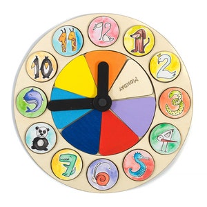 Puede incluir: Un reloj de madera colorido con ilustraciones de animales y números. La esfera del reloj está dividida en 12 secciones, cada una con un animal y un número diferentes. Las manecillas del reloj son negras y apuntan al número 12.
