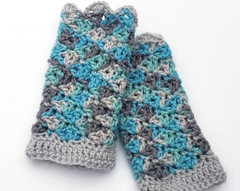 May include: A pair of crocheted fingerless gloves in shades of gray, teal, and blue. The gloves have a scalloped edge and a solid gray band at the wrist.