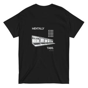 以下が含まれることがあります： グラフィックデザインの黒いTシャツ。デザインは、一連のラップトップスクリーンの上に「MENTALLY」という単語、下に「TABS」という単語を特徴としています。「BETWEEN」というフレーズがラップトップの間で繰り返されています。