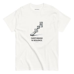 以下が含まれることがあります： 白地のTシャツ。黒と白のドミノが連なったグラフィックと「OVERTHINKING IN SEQUENCE」の文字がプリントされています。クルーネックで半袖。ブランド名「BETWEENIE」が襟にプリントされています。