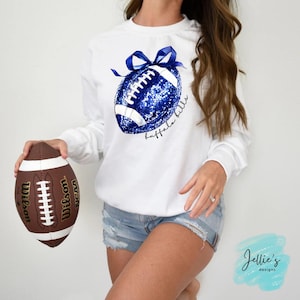 Könnte beinhalten: Weißer Pullover mit einem blauen und weißen Football-Design mit einer blauen Schleife und dem Text "buffalo bills".