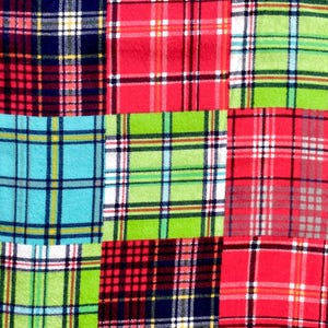 May include: Close-up of a patchwork fabric with a plaid pattern. The fabric features squares of red, green, blue, and white plaid. The squares are arranged in a grid-like pattern, creating a visually interesting design.