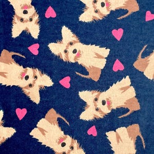 Könnte beinhalten: Ein marineblauer Stoff mit einem sich wiederholenden Muster aus Zeichentrickhunden und rosa Herzen. Die Hunde sind hellbraun und weiß mit schwarzen Augen und Nasen. Die Herzen sind leuchtend rosa.