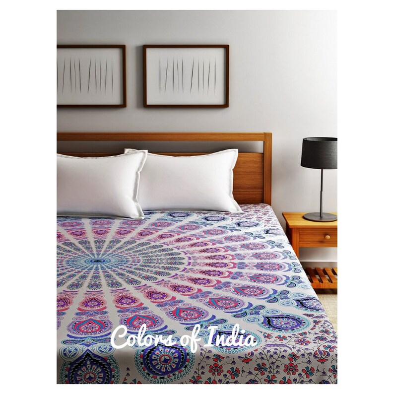 May include: A white bedspread with a colorful mandala design in shades of pink, blue, and purple. The bedspread features a circular pattern with intricate details and a "Colors of India" logo in the center.