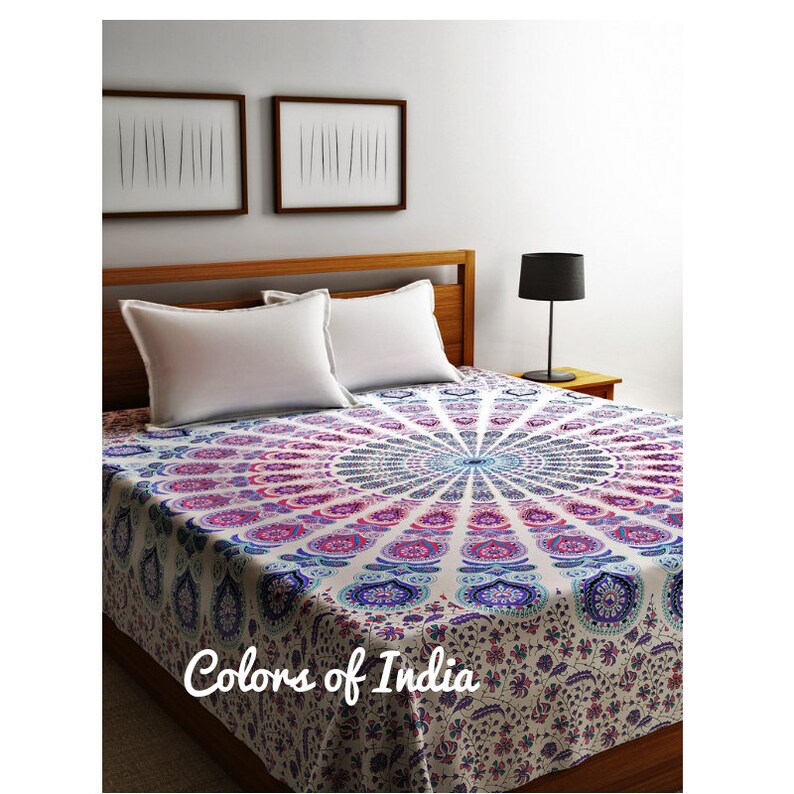 May include: A white bedspread with a large, colorful mandala design in shades of pink, blue, and purple. The bedspread is made of cotton and has a soft, comfortable feel. The text "Colors of India" is printed on the bedspread.