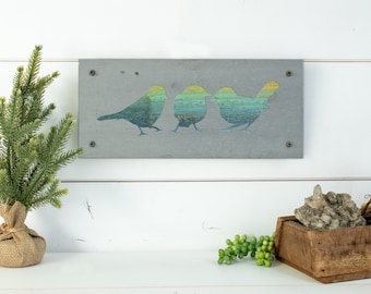 May include: A rectangular gray concrete wall art piece with three birds in a row. The birds are cut out of the concrete and painted in shades of blue and green.