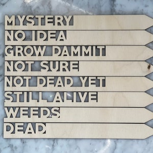 K&ouml;nnte beinhalten: Pflanzenmarkierungen aus Holz mit folgendem Text: "Mystery", "No Idea", "Grow Dammit", "Not Sure", "Not Dead Yet", "Still Alive", "Weeds", "Dead".