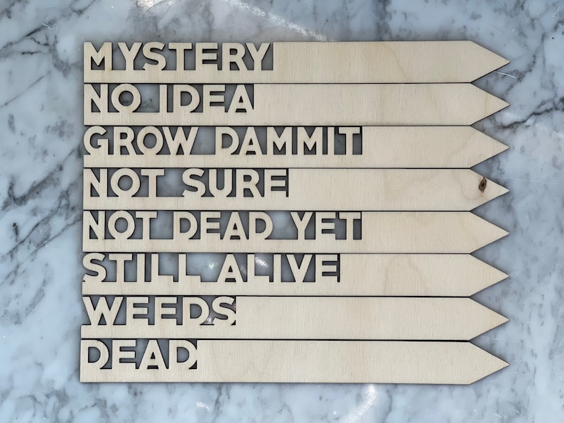 K&ouml;nnte beinhalten: Pflanzenmarkierungen aus Holz mit folgendem Text: "Mystery", "No Idea", "Grow Dammit", "Not Sure", "Not Dead Yet", "Still Alive", "Weeds", "Dead".