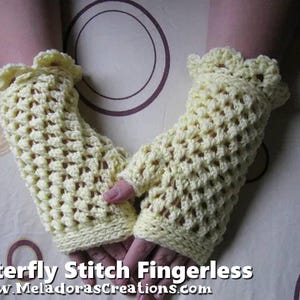 May include: A pair of pale yellow fingerless gloves, crocheted with a butterfly stitch pattern. The gloves have a ruffled edge at the top and are shown on a person's hands. The text "Butterfly Stitch Fingerless" and a website address are visible at the bottom.