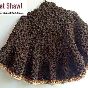May include: A brown Caret Crochet Shawl with a textured pattern and a decorative trim. The shawl is displayed on a hanger against a white background. The text "Caret Crochet Shawl" and a website address are visible in the image.