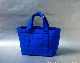 May include: A vibrant royal blue tote bag featuring two sturdy top handles, a rectangular base, and a front exterior pocket. The text "AC" appears in the top right corner, and the text "pdf sewing pattern CHIQUITO" is printed at the bottom.