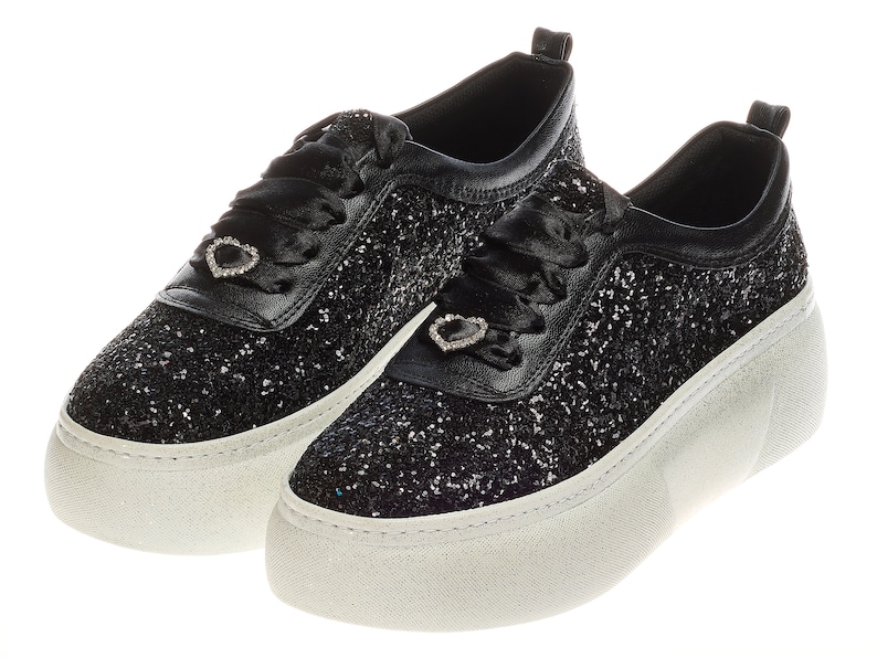 May include: A pair of black glitter platform sneakers with a white sole and a heart-shaped rhinestone embellishment on each shoe.
