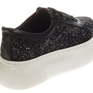May include: Black glitter sneakers with a white platform sole. The sneakers have a lace-up closure.