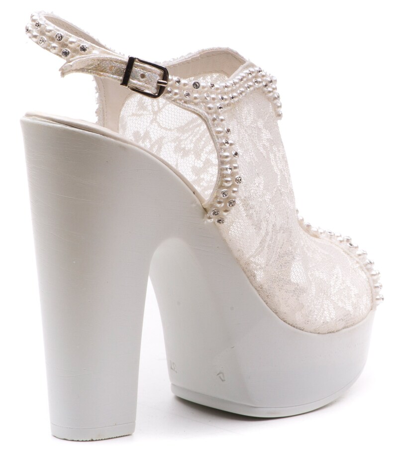 May include: White lace bridal heels with a platform sole and a buckle closure. The heels are decorated with pearl-like embellishments.