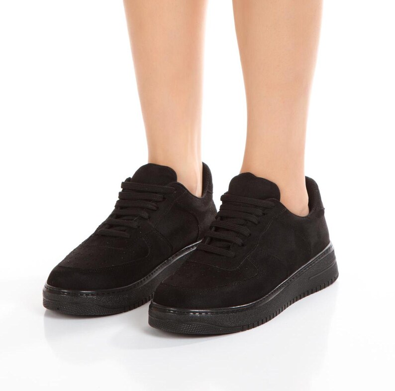 May include: A pair of black suede low-top sneakers with white laces. The sneakers have a thick white sole.