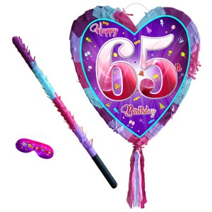 May include: A heart-shaped purple and pink piñata with the number 65 and the text "Happy 65th Birthday". The piñata comes with a stick and a blindfold.