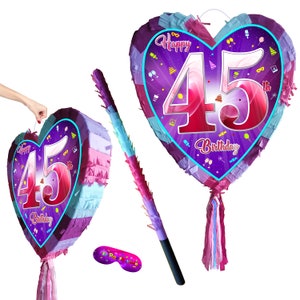May include: A heart-shaped purple and pink pinata with the number 45 and the text "Happy 45th Birthday". The pinata comes with a stick and a blindfold.