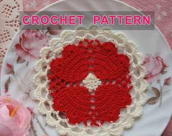 Peut inclure: Un napperon en crochet rouge et blanc avec un bord festonné. Le napperon est sur une assiette blanche avec un motif floral. Le texte "CROCHET PATTERN" est en haut de l'image.