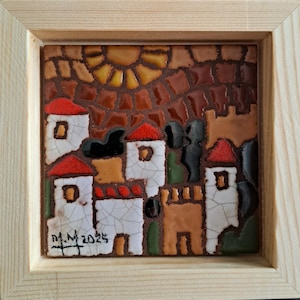 Puede incluir: Una obra de arte en mosaico enmarcada que representa una escena de pueblo con edificios blancos, tejados rojos y un sol. La obra está enmarcada en un marco de madera natural. Firmado y fechado "M.M. 2025".
