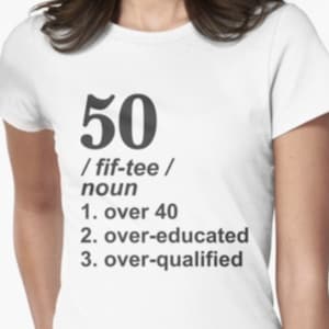 May include: White t-shirt with black text that reads "50 /fif-tee/ noun 1. over 40 2. over-educated 3. over-qualified"