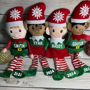 Può includere: Quattro bambole di peluche a forma di elfo con cappelli rossi con fiocchi di neve bianchi, abiti verdi e rossi e gambe a righe. Ogni elfo ha un nome diverso sulla camicia: Smith, Kyah, Maddy e Grayson. L'anno 2024 è stampato sui piedi.