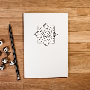 May include: A white notebook with a geometric design on the cover. The notebook is on a wooden surface with a pencil and several dice.