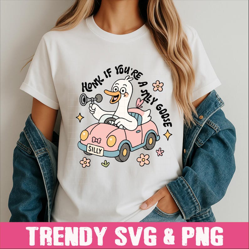 Peut inclure: T-shirt blanc avec un dessin d'oie de dessin anim&eacute; conduisant une voiture rose et klaxonnant. Le texte "Honk if you're a silly goose" est au-dessus de l'oie, avec le mot "Silly" sur la plaque d'immatriculation de la voiture. Des graphiques floraux et en forme d'&eacute;toiles entourent le dessin.
