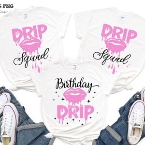 以下が含まれることがあります： ピンクと黒のグラフィックデザインが施された白いTシャツ3枚。シャツには「Drip Squad」と「Birthday Drip」の文字と、ピンクの垂れ下がった唇のデザインが施されています。