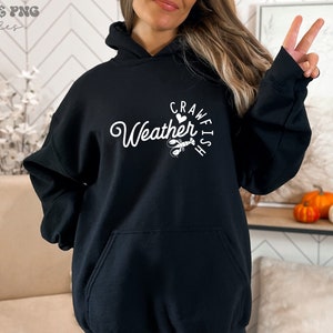 May include: Black hooded sweatshirt with white text that reads "Crawfish Weather" with a heart and a crawfish illustration.