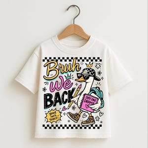 May include: White t-shirt featuring a cartoon goose wearing sunglasses, a checkered hat, and leopard print shoes. The goose carries a backpack and a notebook that says "Day One Drama." The shirt has the words "Bruh We Back" in colorful text.