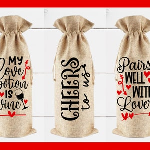 May include: Three burlap wine bottle bags with different Valentine's Day themed sayings. The first bag says "My love potion is wine". The second bag says "Cheers to us". The third bag says "Pairs well with lover".