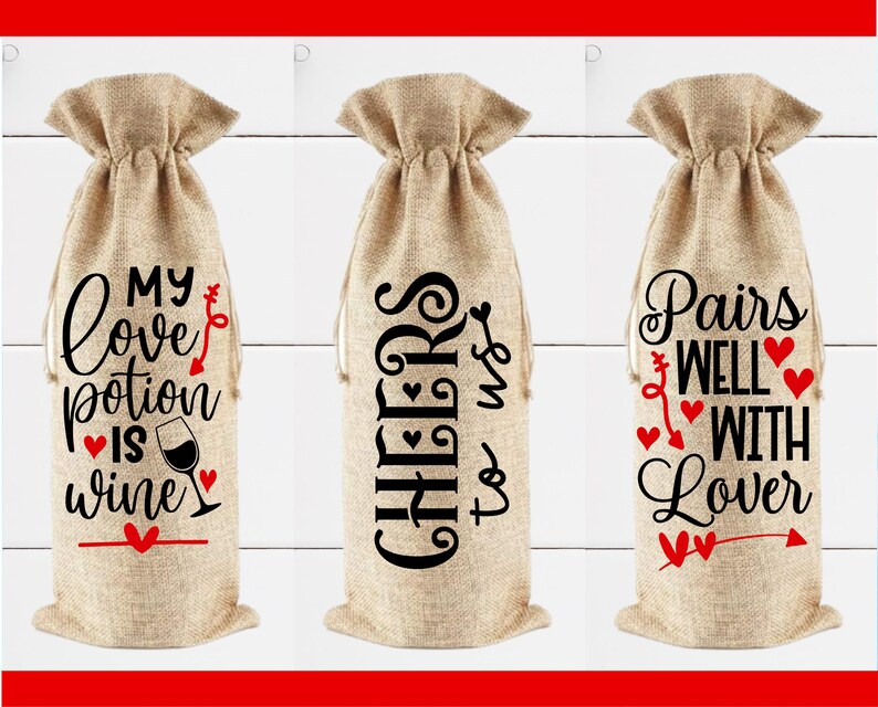 May include: Three burlap wine bottle bags with different Valentine's Day themed sayings. The first bag says "My love potion is wine". The second bag says "Cheers to us". The third bag says "Pairs well with lover".