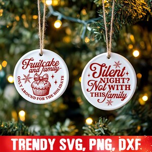May include: Two white round Christmas ornaments with red text. The first ornament says "Fruitcake and family only around for the holidays". The second ornament says "Silent night? Not with this family".