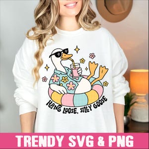 Peut inclure: Sweat-shirt blanc avec un dessin d'oie en lunettes de soleil et chemise hawa&iuml;enne, se relaxant dans une bou&eacute;e color&eacute;e et buvant une boisson. Le texte dit "Hang Loose, Silly Goose".