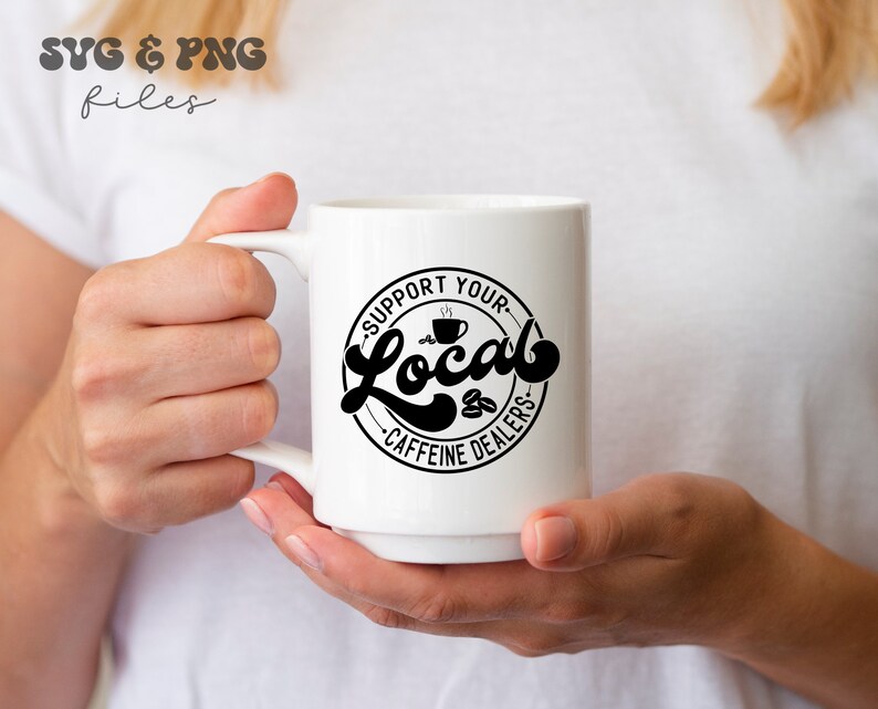 May include: White ceramic mug with a black circle design that says "Support Your Local Caffeine Dealers" with a coffee cup icon.