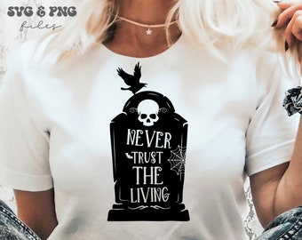 May include: A white t-shirt with a black graphic of a tombstone with a skull and crossbones, a crow, and the text "Never Trust The Living".