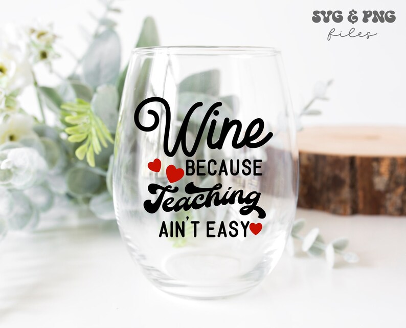May include: A clear glass wine glass with the text "Wine because teaching ain't easy" in black lettering with red hearts.