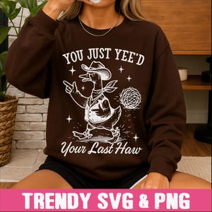 May include: Brown sweatshirt with a white graphic of a cowboy duck with the text "You Just Yee'd Your Last Haw".